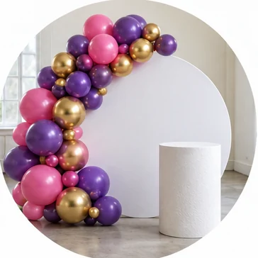 White backdrop and plinth with a pink, purple and gold balloon garland